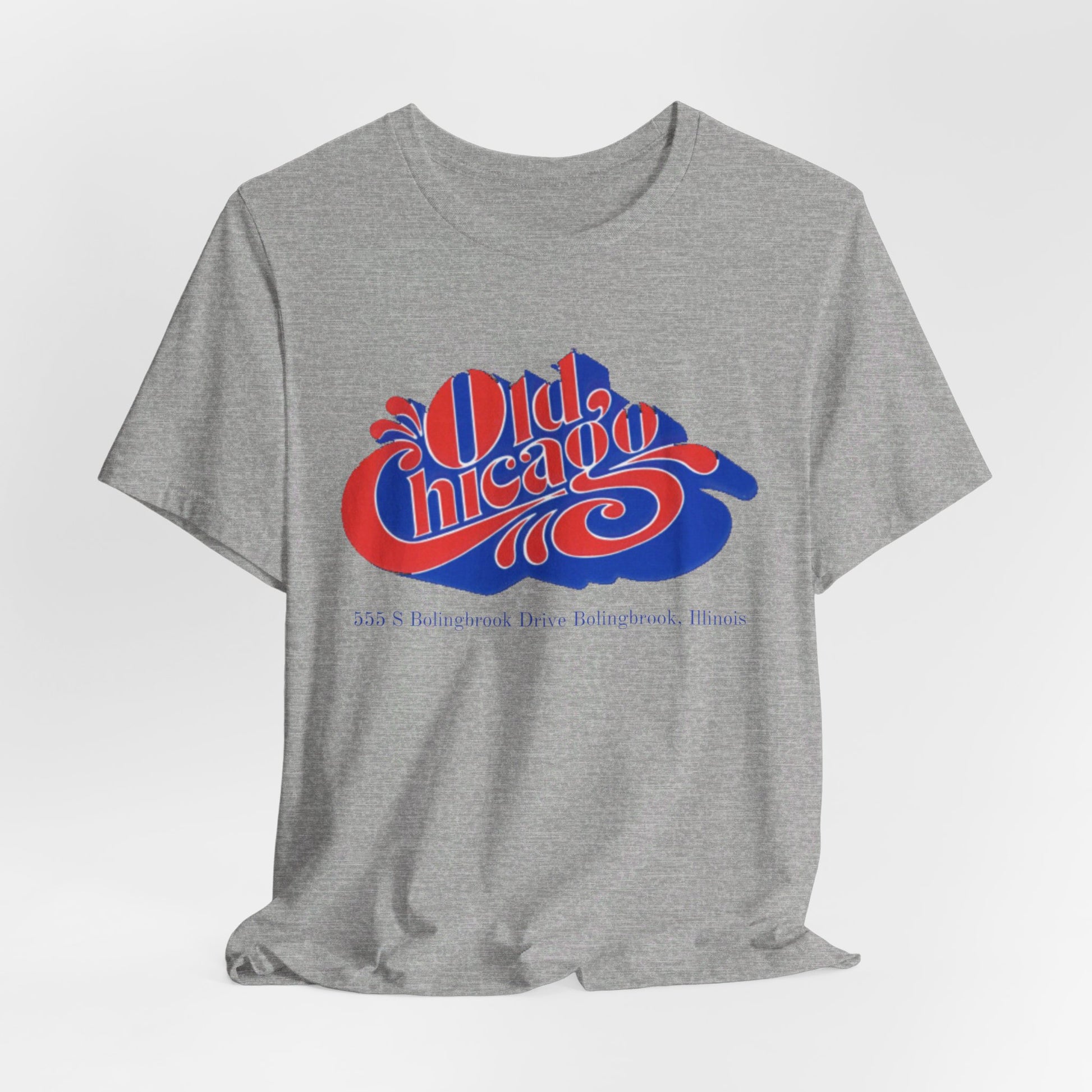 The "Old Chicago Mall Bolingbrook 1980s Retro - Unisex Jersey Short Sleeve Tee" from Printify is a gray T-shirt showcasing a vintage design with the text "Old Chicago" in blue and red. Beneath the main text, the address "355 S. Bolingbrook Drive, Bolingbrook, Illinois" appears in smaller font, evoking 80s nostalgia of the Old Chicago Mall. The shirt is displayed against a white background.