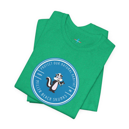 The Printify Miller Beach Skunks - Unisex Jersey Short Sleeve Tee is a gray T-shirt that features a circular blue logo at the center. Inside the logo, there is an illustration of a skunk with the text "Protect Our Habitat" and "Miller Beach Skunks" around the border, promoting environmental consciousness. The upper left part of the logo reads "Gary, IN.