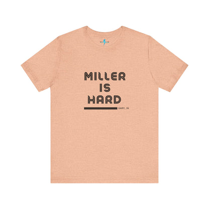 A unisex jersey short sleeve tee from Printify in burnt orange features the bold black text "MILLER IS HARD" on the chest, with "GARY, IN" written beneath in smaller black font. Perfect for showcasing Miller Beach's iconic spirit, this t-shirt is displayed against a plain white background.