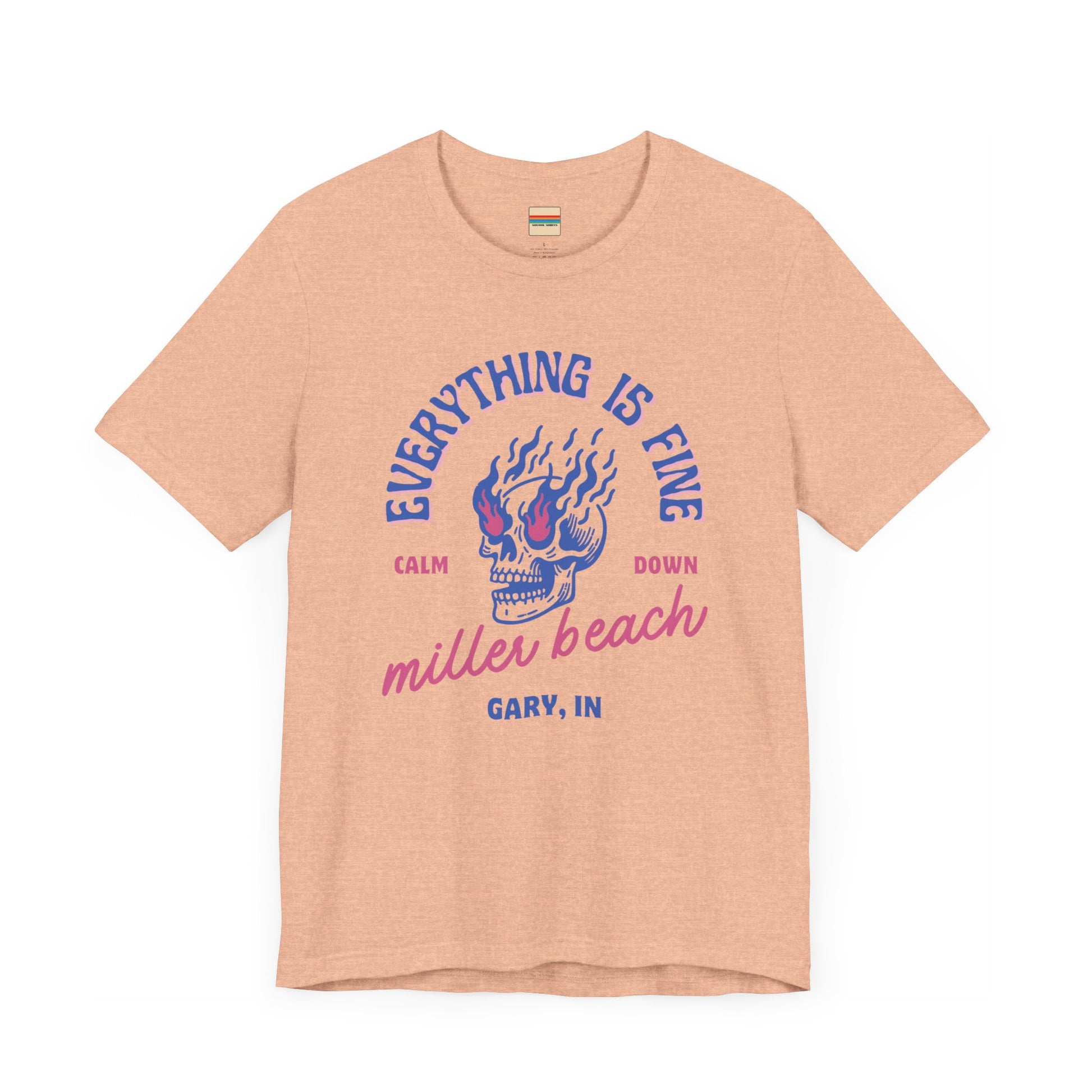 The Miller Beach Calm Down Everything is Fine - Unisex Jersey Short Sleeve Tee from Printify, crafted from soft Airlume combed cotton, showcases a peach-colored design with a flaming skull in the center. Above the design, it reads "Everything is fine," and below it says, "Calm down Miller Beach." In smaller text at the bottom, it reads "Gary, IN.