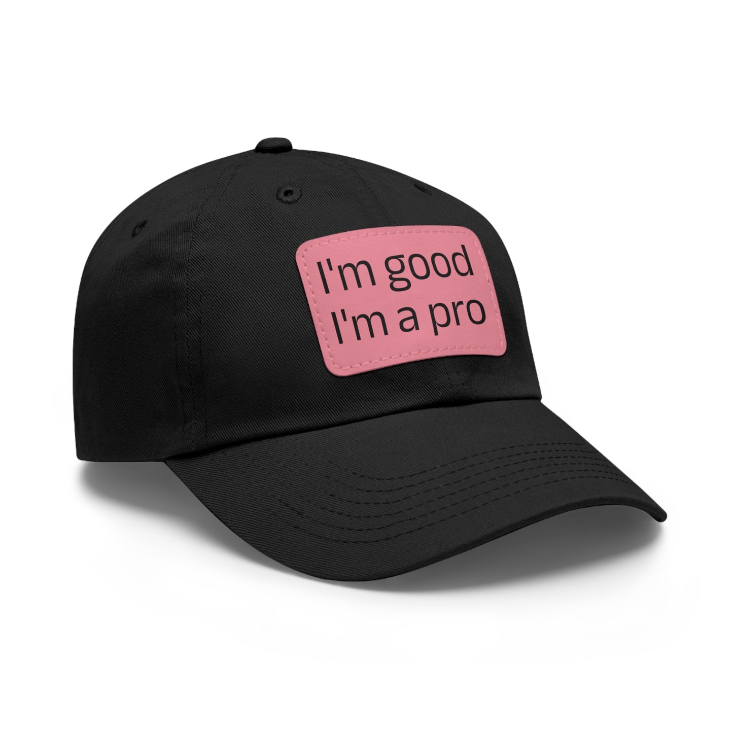 The Printify Dad Hat with Leather Patch (Rectangle) is a black, six-panel low-profile baseball cap made from bio-washed chino twill. This personalized Dad hat features a curved brim, visible stitching details, and a rectangular leather patch on the front that reads "I'm good I'm a pro" in grey text.