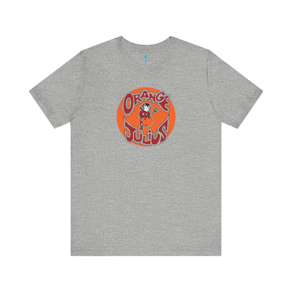 The Orange Julius 1980's Logo Unisex Jersey Style T-Shirt from Printify boasts a light gray color and features a vintage-style graphic. The design showcases the text "Orange Julius" in a stylized font within an orange circle, along with a small cartoon character holding a drink at the center—a nostalgic nod to timeless refreshment.