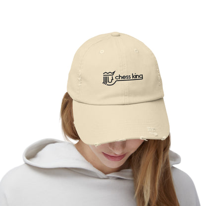 The 1980s Chess King Clothing Store Logo - Unisex Distressed Cap by Printify is a beige baseball cap made from 100% cotton twill. It features intentional distress details and a logo with a crown and rook piece, along with the text "chess king" embroidered on the front, making it a stylish choice for custom caps enthusiasts.