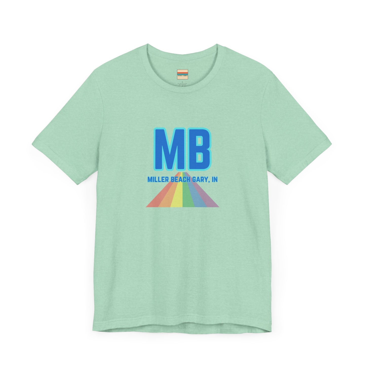 The Miller Beach Pride - Unisex Jersey Short Sleeve Tee by Printify is a white shirt made from 100% Airlume combed cotton. It showcases a design with large, bold blue letters "MB" at the top. Beneath it, the text "MILLER BEACH GARY, IN" is written in blue. A colorful, triangular rainbow graphic extends downward from the text, symbolizing Miller Beach pride.