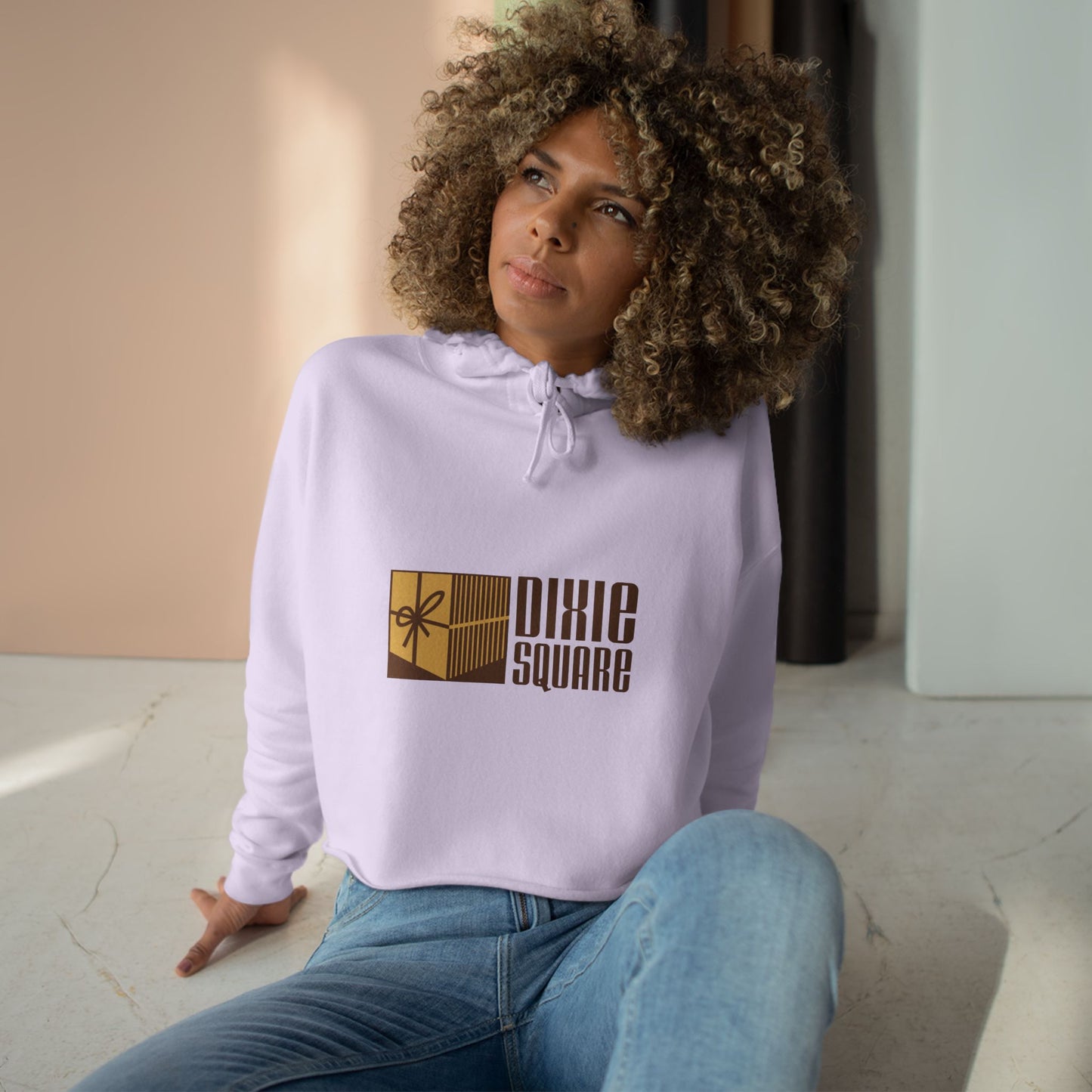 Pink cropped hoodie from Printify, showcasing a yellow and brown "Dixie Square" logo with a ribbon design on the front, reminiscent of the iconic Dixie Square Mall in Harvey, IL from the Blues Brothers era.