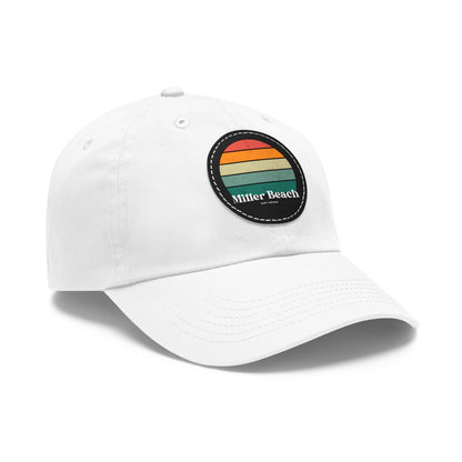 The Miller Beach Retro Sunset - Dad Hat with Leather Patch (Round) by Printify is a pink baseball cap crafted from bio-washed chino twill for added comfort. It features a PU leather patch adorned with horizontal stripes in red, orange, yellow, green, and blue. Below the stripes, "Miller Beach" is embroidered in white. An adjustable strap at the back ensures a perfect fit.