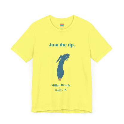 The Just the Tip - Miller Beach Unisex Jersey Short Sleeve Tee by Printify in yellow showcases text and a graphic design. The top displays "Just the tip" above a blue silhouette reminiscent of Indiana. At the bottom, it reads "Miller Beach" and "Gary, IN." Made from soft Airlume combed cotton, this tee offers both comfort and style.