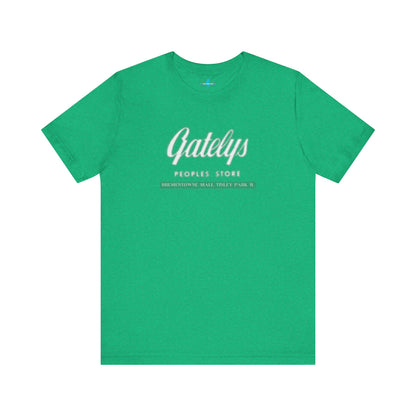 A green unisex jersey short sleeve tee from Printify's SoCool Shirts collection, featuring "Gately's People's Store" printed prominently in white on the front. Below this, smaller text reads "Tinley Park's Brementowne Mall" in white. The T-shirt is displayed against a plain white background and is named the "Gatelys Peoples Store - Vintage 1980s.