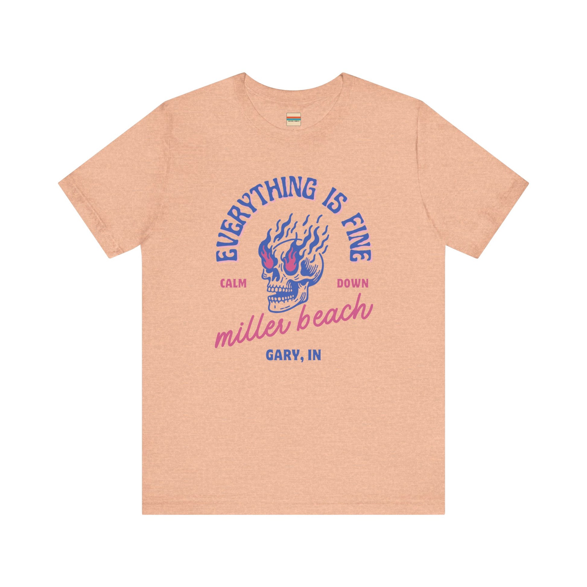 The Miller Beach Calm Down Everything is Fine - Unisex Jersey Short Sleeve Tee from Printify, crafted from soft Airlume combed cotton, showcases a peach-colored design with a flaming skull in the center. Above the design, it reads "Everything is fine," and below it says, "Calm down Miller Beach." In smaller text at the bottom, it reads "Gary, IN.