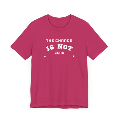 Folded light red Unisex Jersey Short Sleeve Tee from Printify, featuring bold white text that reads "THE CHANCE IS NOT ZERO" along with two star illustrations. This motivational T-shirt, made from breathable fabric, is neatly stacked with another identical shirt underneath.