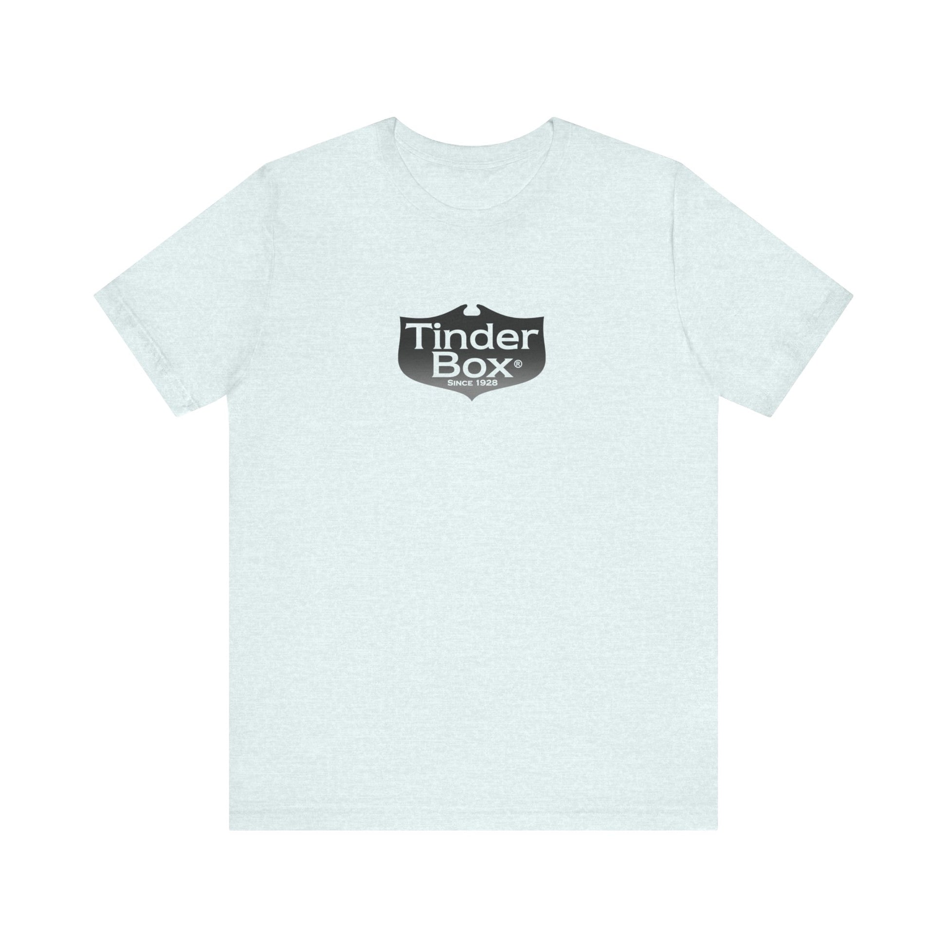 A light blue Printify "The Tinder Box 1980s" unisex jersey short sleeve tee featuring the "Tinder Box" logo in the center. The logo consists of a dark shield with the words "Tinder Box" in white text, with a small flame icon replacing the dot above the "i".