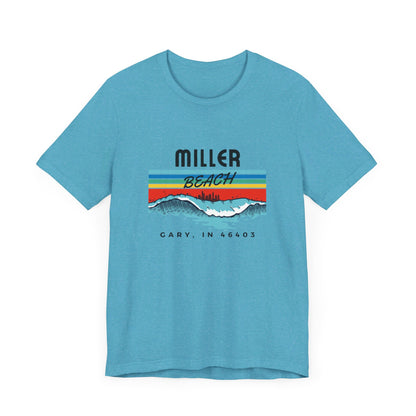 The Miller Beach 46403 Surf Style - Unisex Jersey Short Sleeve Tee by Printify features a retro surf-inspired design on a yellow background. The shirt displays "MILLER BEACH" above waves with a skyline illustration, while "Cary, IN 46403" is printed below the waves. The vibrant design also includes colorful stripes in shades of blue, red, and orange.