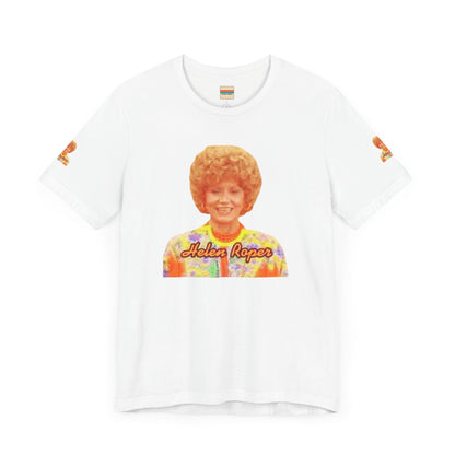 A lavender-colored Helen (Mrs.) Roper Three's Company - Unisex Jersey Short Sleeve Tee by Printify is hanging on a wooden hanger against a white background. This T-shirt features an image of a smiling person with curly hair wearing a colorful blouse, with the text "Helen Roper" underneath the image. Both sleeves have identical designs, making it perfect Three's Company merchandise.