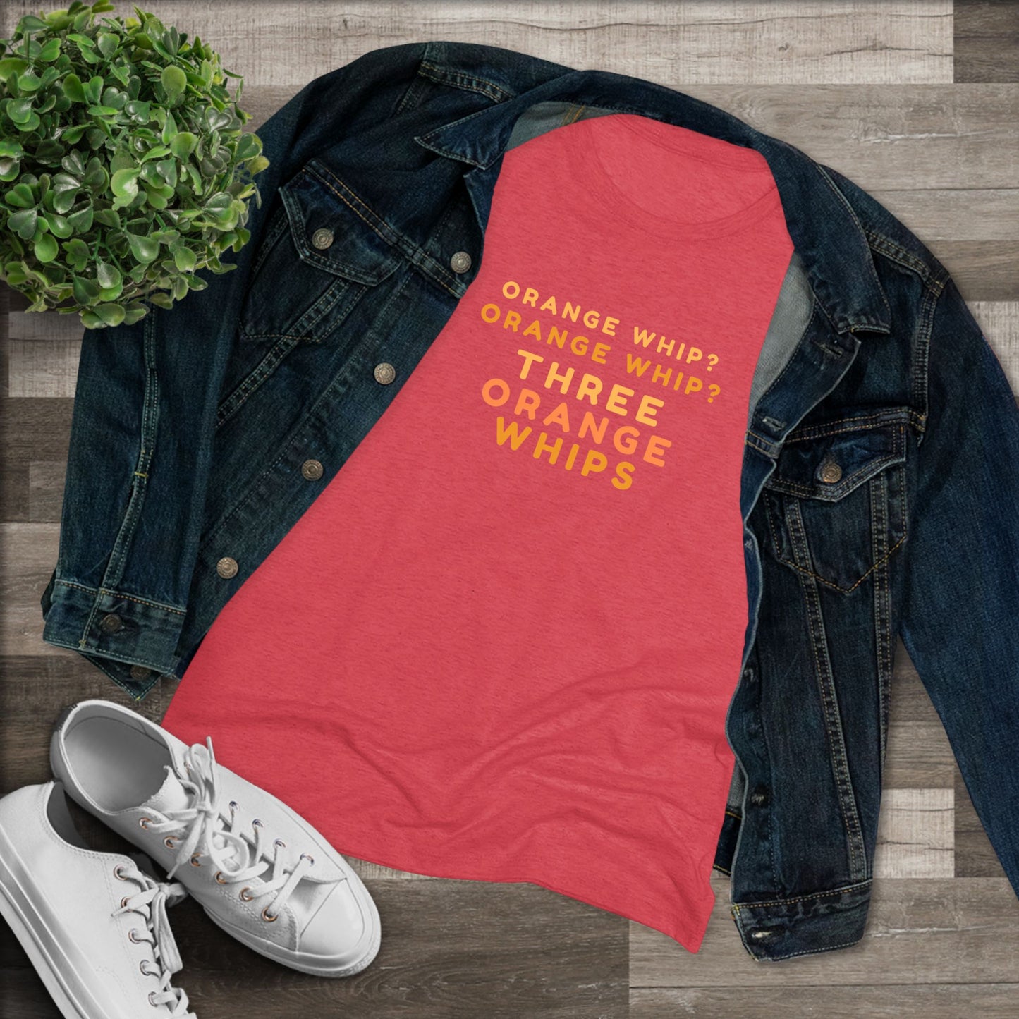 This Blues Brothers women's triblend tee from Printify features a dark gray vintage look with the text "ORANGE WHIP? ORANGE WHIP? THREE ORANGE WHIPS" printed in bright orange and yellow in the center. With a round neck and short sleeves, it's perfect for that retro vibe.