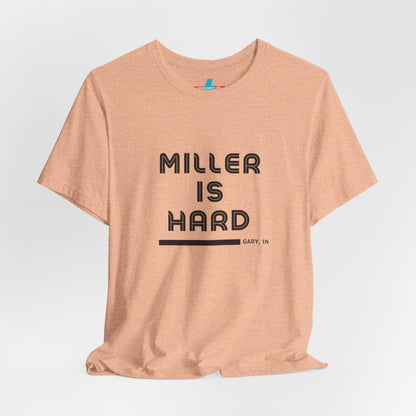 A unisex jersey short sleeve tee from Printify in burnt orange features the bold black text "MILLER IS HARD" on the chest, with "GARY, IN" written beneath in smaller black font. Perfect for showcasing Miller Beach's iconic spirit, this t-shirt is displayed against a plain white background.