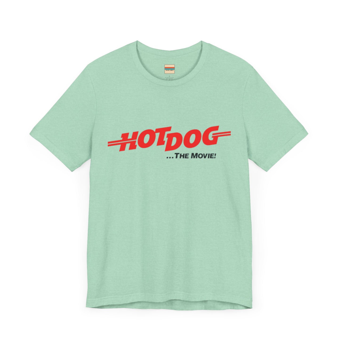 A smiling man and woman interact while wearing matching yellow "Hot Dog The Movie 1984 - Unisex Jersey Short Sleeve Tee" by Printify, featuring bold red "HOT DOG THE MOVIE" text. Their vibrant tees perfectly complement their blue jeans, with the man casually having his hands in his pockets and the woman resting one hand on his shoulder.