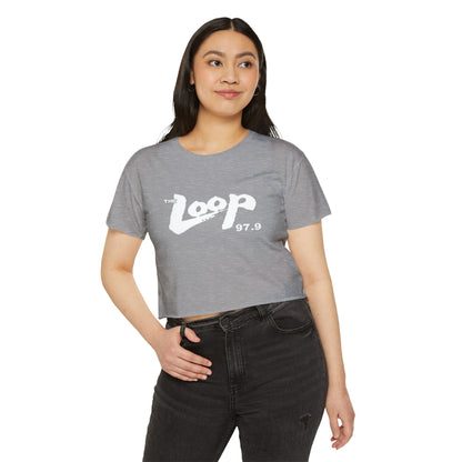 Printify's Women's Festival Crop Top features a grey design with short sleeves and a round neckline. The crop top displays the text "The Loop 97.9" in white, with the word "Loop" styled in a brushstroke-like font—ideal for fans of Chicago’s iconic rock radio station who appreciate retro fashion.