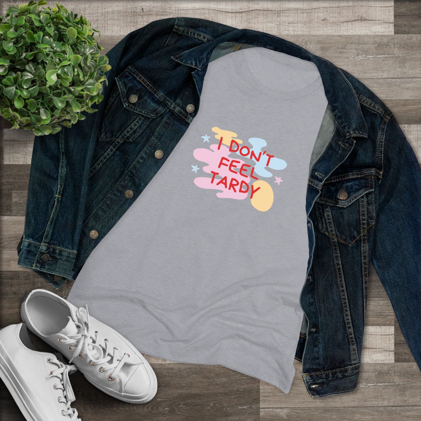 A light gray, short-sleeved Women's Triblend Tee from Printify with the playful phrase "I DON'T FEEL TARDY" printed in colorful letters on the front. The text is surrounded by abstract pastel shapes, giving it retro vibes and a vintage look reminiscent of a Van Halen T-shirt.