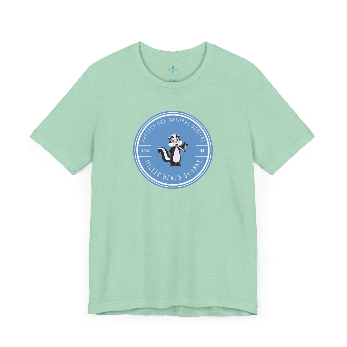 The Printify Miller Beach Skunks - Unisex Jersey Short Sleeve Tee is a gray T-shirt that features a circular blue logo at the center. Inside the logo, there is an illustration of a skunk with the text "Protect Our Habitat" and "Miller Beach Skunks" around the border, promoting environmental consciousness. The upper left part of the logo reads "Gary, IN.