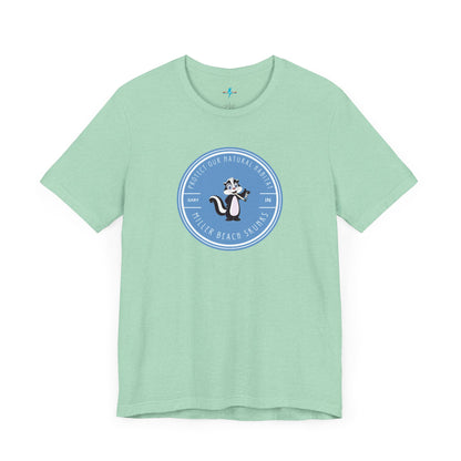 The Printify Miller Beach Skunks - Unisex Jersey Short Sleeve Tee is a gray T-shirt that features a circular blue logo at the center. Inside the logo, there is an illustration of a skunk with the text "Protect Our Habitat" and "Miller Beach Skunks" around the border, promoting environmental consciousness. The upper left part of the logo reads "Gary, IN.