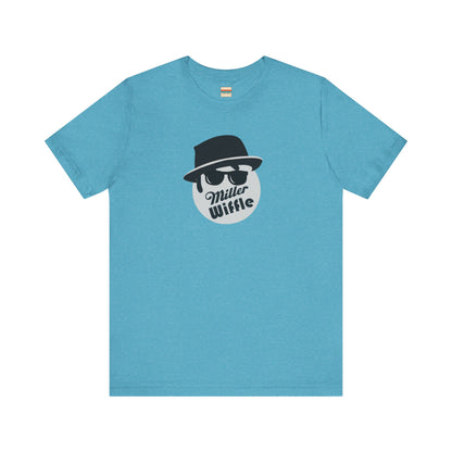 A purple unisex jersey tee from Printify, named the "Miller Wiffel Ball - Blues Brothers - Unisex Jersey Short Sleeve Tee," features a stylized graphic of a ball wearing a black fedora and sunglasses with the text "Miller Wiffel" below it. Another identical soft cotton t-shirt is neatly folded underneath, highlighting its breathable fabric.