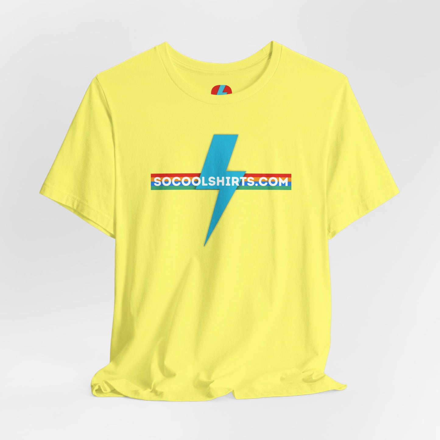 This unisex jersey short sleeve tee by Printify features a striking maroon color with a central light blue lightning bolt design. The text "SOCOOLSHIRTS.COM" is prominently displayed across the lightning bolt in white letters, set against a multicolored background that exudes retro vibes. The shirt is shown laid flat on a white backdrop.