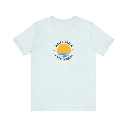 The Miller Beach Gary Indiana EST 1851 - Unisex Jersey Short Sleeve Tee by Printify is a classic blue unisex shirt featuring a vibrant graphic design of a yellow sun setting over blue waves. The text surrounding the artwork reads "Miller Beach" at the top and "Gary Indiana" at the bottom, making it an ideal tribute to this cherished location.