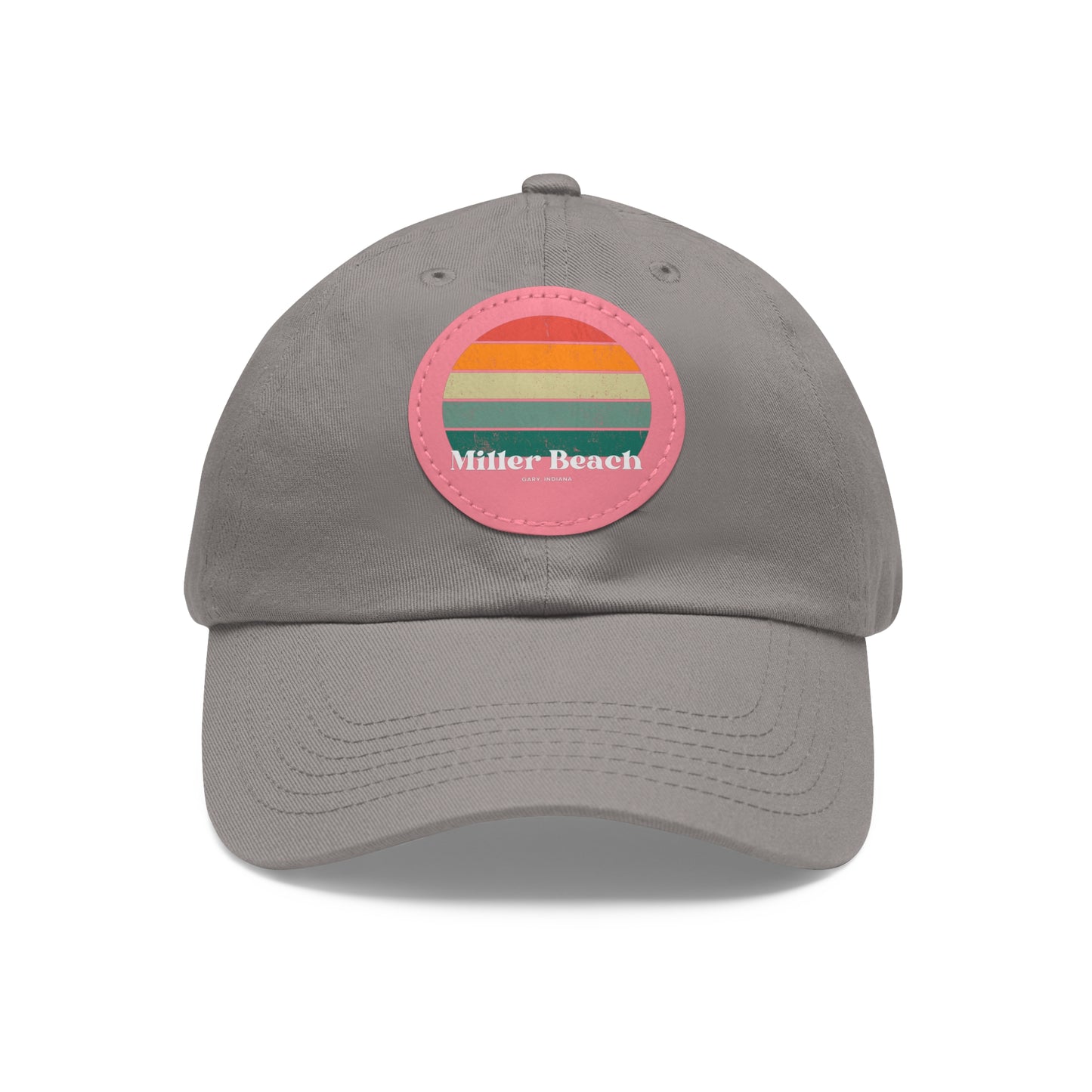 The Miller Beach Retro Sunset - Dad Hat with Leather Patch (Round) by Printify is a pink baseball cap crafted from bio-washed chino twill for added comfort. It features a PU leather patch adorned with horizontal stripes in red, orange, yellow, green, and blue. Below the stripes, "Miller Beach" is embroidered in white. An adjustable strap at the back ensures a perfect fit.