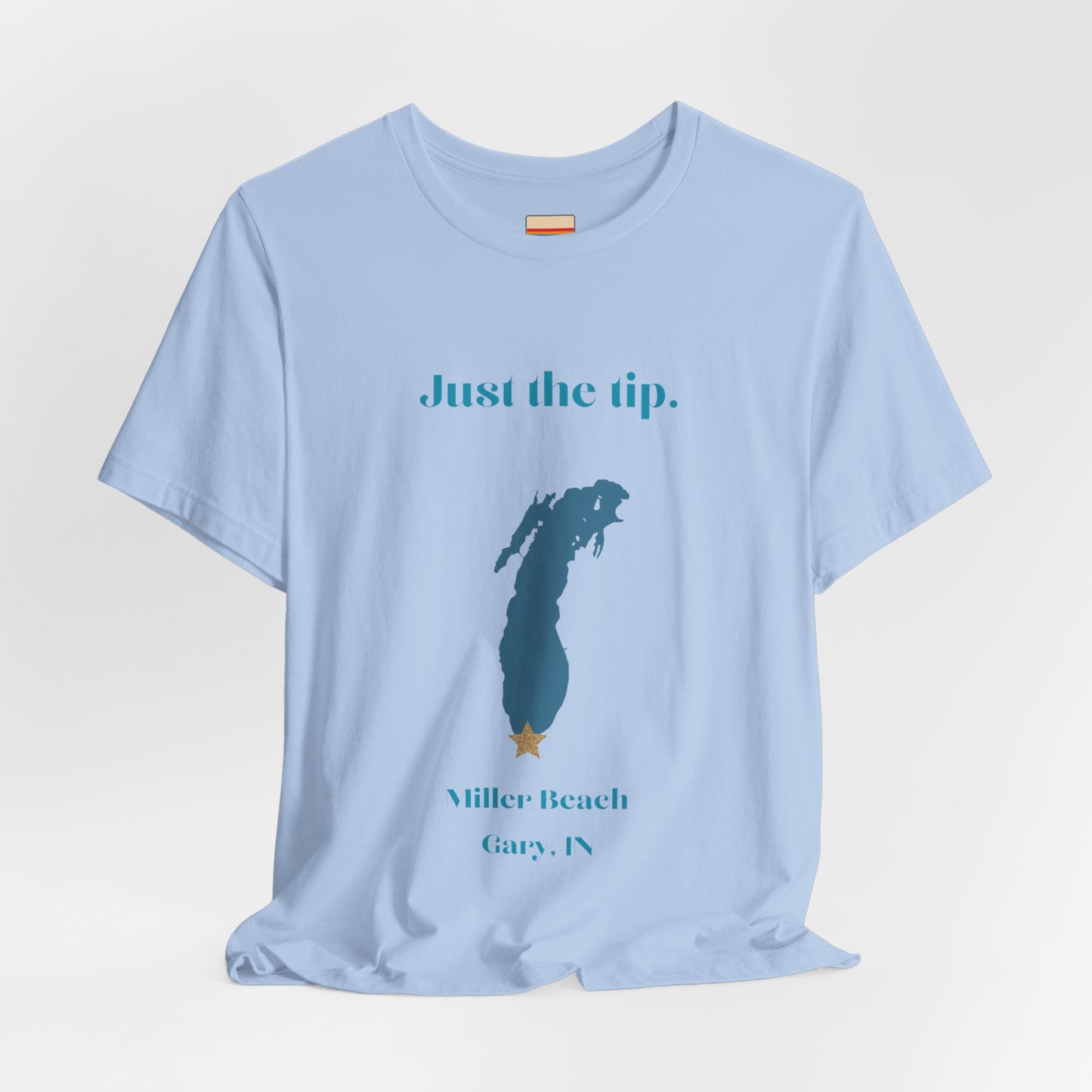 The Just the Tip - Miller Beach Unisex Jersey Short Sleeve Tee by Printify in yellow showcases text and a graphic design. The top displays "Just the tip" above a blue silhouette reminiscent of Indiana. At the bottom, it reads "Miller Beach" and "Gary, IN." Made from soft Airlume combed cotton, this tee offers both comfort and style.