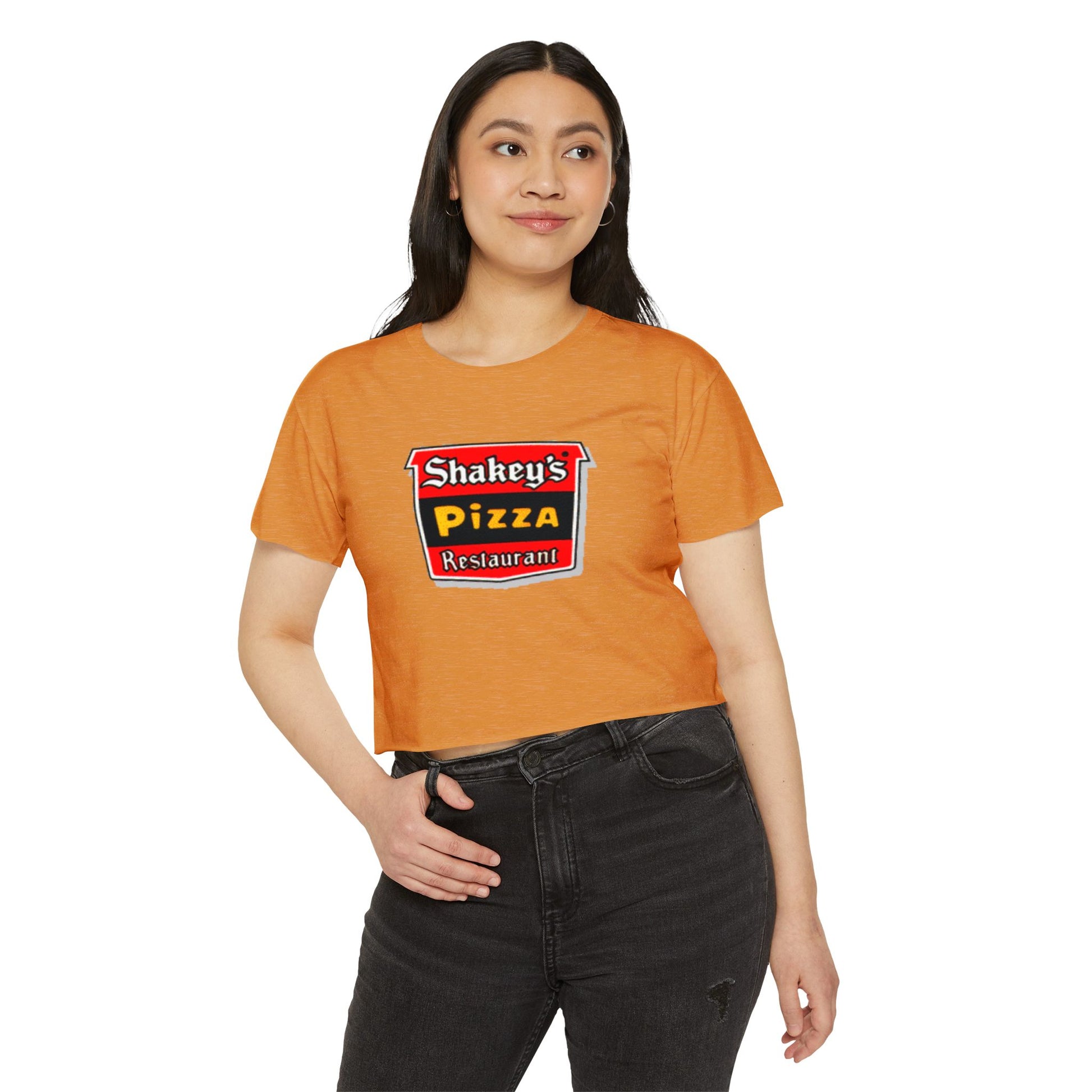 The Shakey's Pizza - Women's Festival Crop Top from Printify is a light blue garment that proudly displays the iconic Shakey's Pizza logo on the chest. Featuring retro-style red and black signage with text in white, yellow, and red that reads "Shakey's Pizza Restaurant," this crop top exudes a vintage-inspired charm.