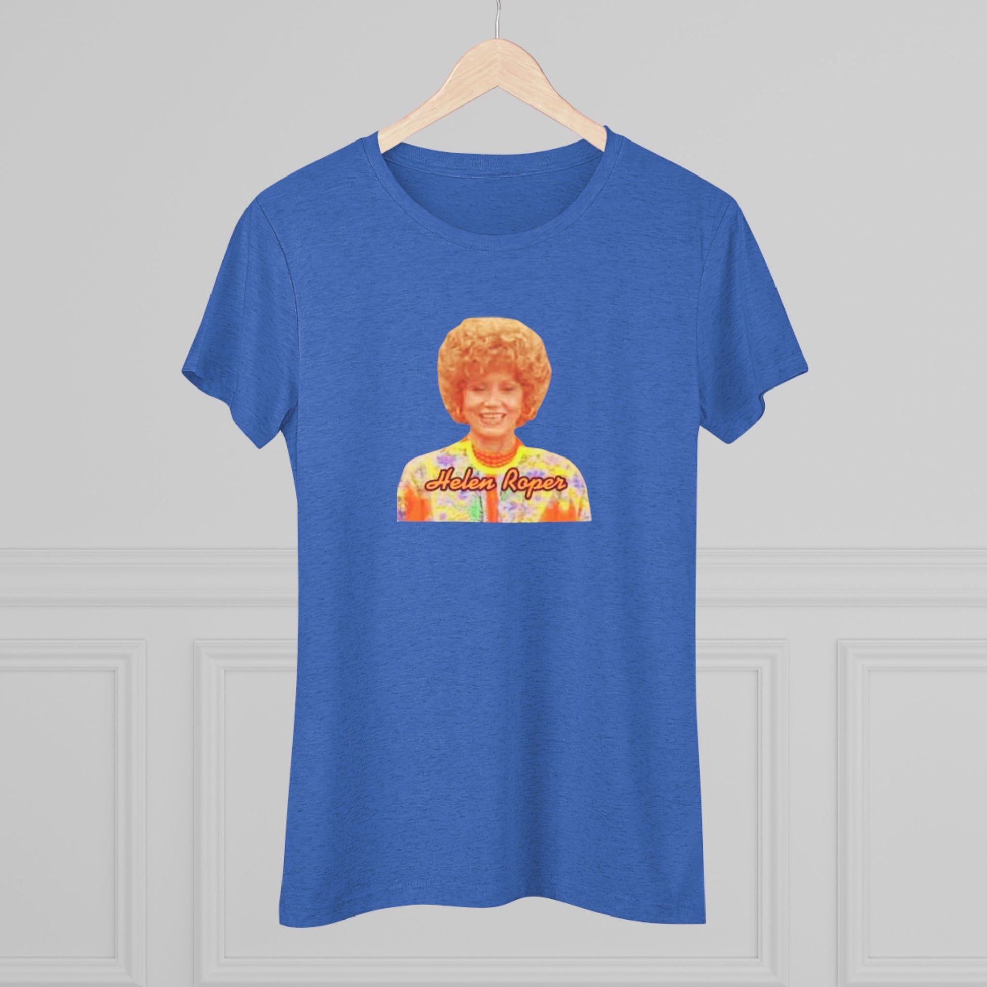 A Women's Triblend Tee by Printify, titled "Helen Roper - Three's Company," features a red design with an illustration of a smiling person with curly hair and colorful clothing. Below the illustration, the text "Helen Roper" is written in a bold, retro font, capturing the essence of vintage TV humor.