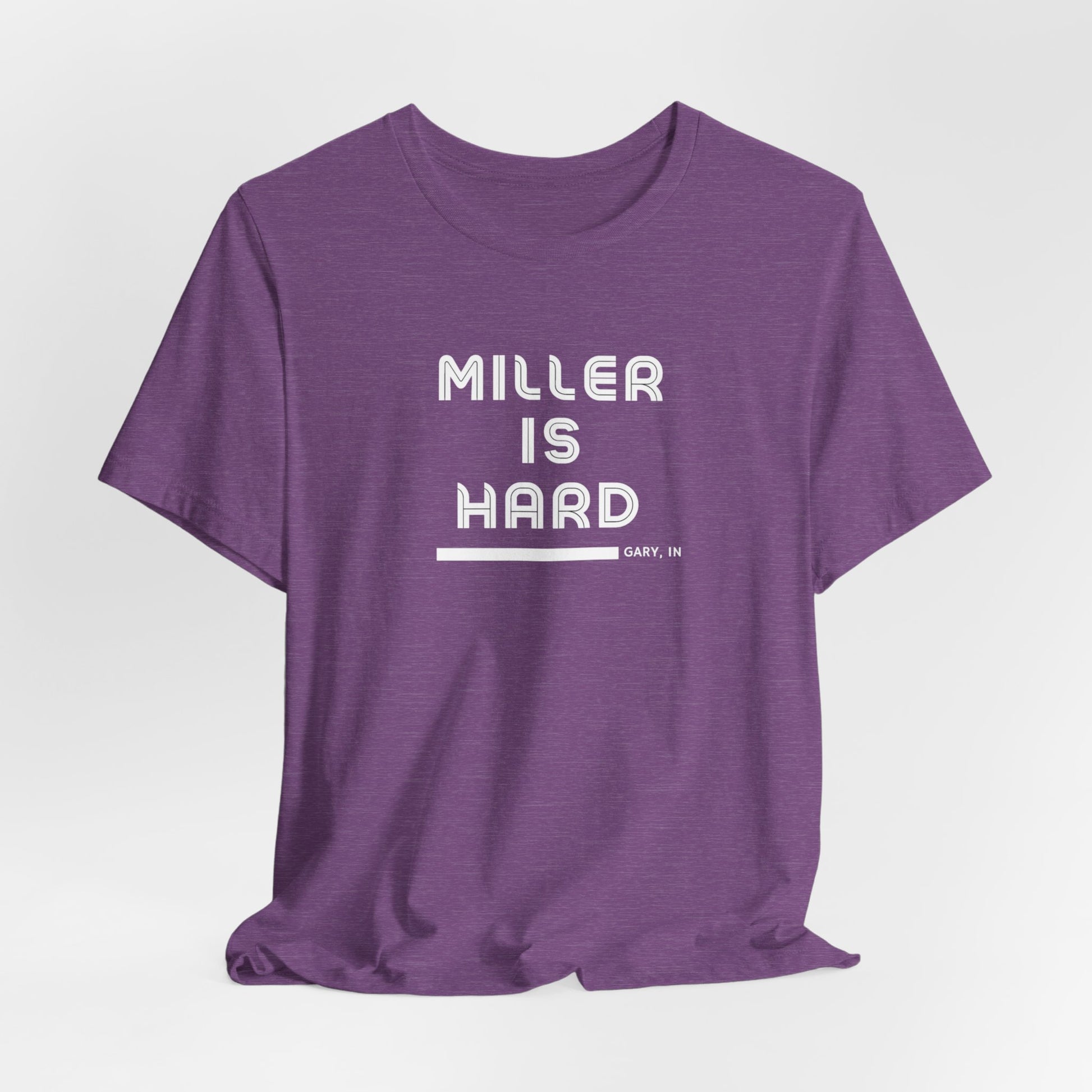 The Miller is Hard - White Letters - Unisex Jersey Short Sleeve Tee by Printify features a rust-colored design with "MILLER IS HARD" printed in bold, white capitals on the front. Below, "GARY, IN." is added in smaller font. This simple yet striking shirt evokes the spirit of Miller Beach with no additional graphics or patterns.