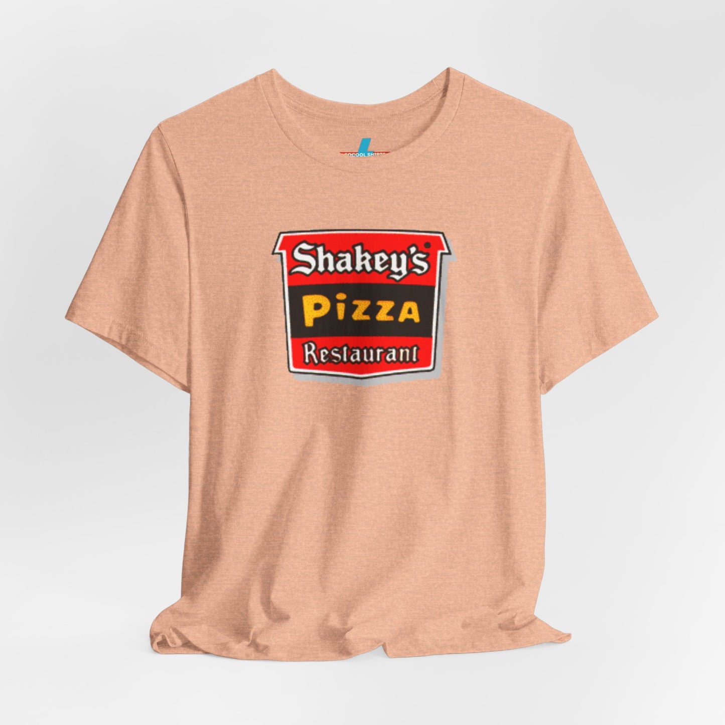 A black Shakey's Pizza - 1980s Retro Logo - Unisex T-Shirt by Printify hangs against a white background. The shirt features a colorful graphic with the text "Shakey's Pizza Restaurant" in white, yellow, and black lettering on a red background, resembling vintage pizza joints signage. This retro tee brings nostalgic vibes of classic pizzerias.