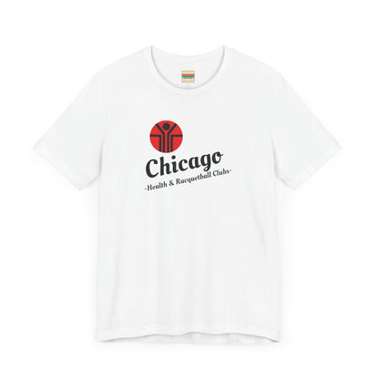 Two gray T-shirts are neatly folded on top of each other, with the top shirt showcasing the text "Chicago Health & Racquetball Clubs" in black below a red logo featuring a person with raised arms inside a circular design. This retro-inspired tee, named "Chicago Health Clubs 1980s Retro - Unisex Jersey Short Sleeve Tee" by Printify, is perfect for any fan of Chicago Health Clubs.