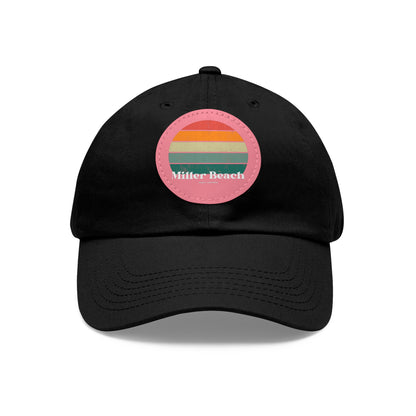 The Miller Beach Retro Sunset - Dad Hat with Leather Patch (Round) by Printify is a pink baseball cap crafted from bio-washed chino twill for added comfort. It features a PU leather patch adorned with horizontal stripes in red, orange, yellow, green, and blue. Below the stripes, "Miller Beach" is embroidered in white. An adjustable strap at the back ensures a perfect fit.