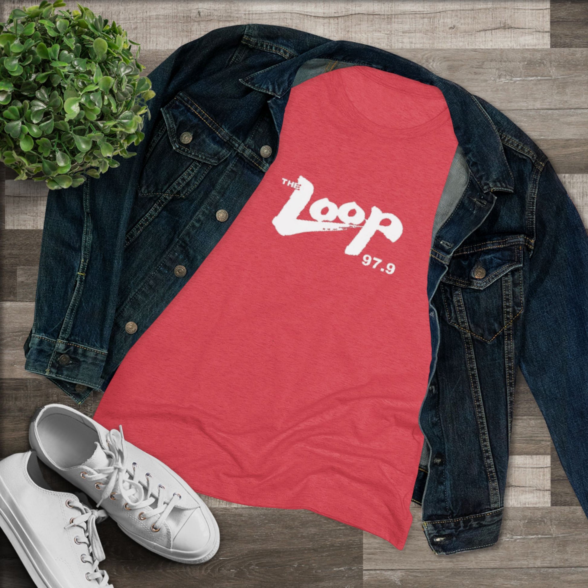 A dark gray, premium tri-blend fabric t-shirt with "The Loop - Chicago Radio 97.9" printed in white text across the chest. The casual, slightly distressed style of the text gives it a vintage look. The classic rock t-shirt is laid flat against a white background. This women's triblend tee by Printify offers a stylish homage to vintage radio days.