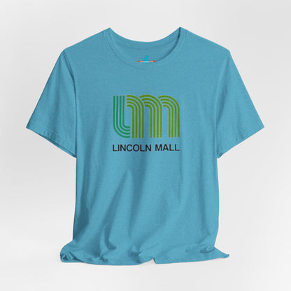 A light green unisex jersey short sleeve tee by Printify features "LINCOLN MALL" written under a retro-styled green and blue curved line design, celebrating the 70s and 80s shopping era in Lincoln Mall Matteson.