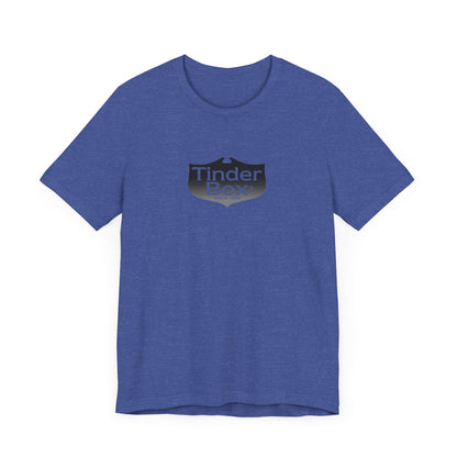 A light blue Printify "The Tinder Box 1980s" unisex jersey short sleeve tee featuring the "Tinder Box" logo in the center. The logo consists of a dark shield with the words "Tinder Box" in white text, with a small flame icon replacing the dot above the "i".