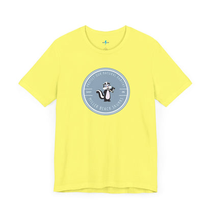 The Printify Miller Beach Skunks - Unisex Jersey Short Sleeve Tee is a gray T-shirt that features a circular blue logo at the center. Inside the logo, there is an illustration of a skunk with the text "Protect Our Habitat" and "Miller Beach Skunks" around the border, promoting environmental consciousness. The upper left part of the logo reads "Gary, IN.