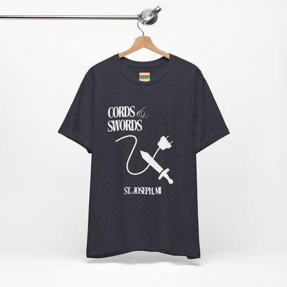 The SoCool Podcast - Cords & Swords Store T-Shirt by Printify is a vintage-inspired blue shirt that showcases a white graphic with the text "Cords & Swords" above illustrations of a crossed power cord and sword, along with "St. Joseph, MI" beneath. Ideal for tech enthusiasts, this design is centered on the front against a plain white background.