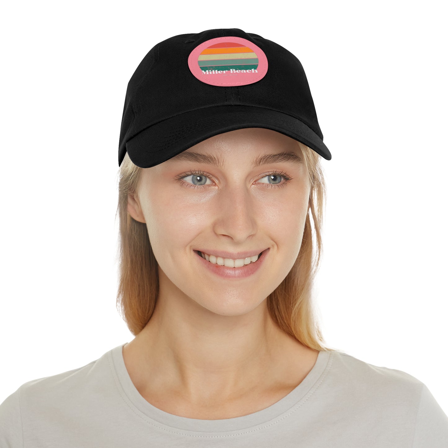 The Miller Beach Retro Sunset - Dad Hat with Leather Patch (Round) by Printify is a pink baseball cap crafted from bio-washed chino twill for added comfort. It features a PU leather patch adorned with horizontal stripes in red, orange, yellow, green, and blue. Below the stripes, "Miller Beach" is embroidered in white. An adjustable strap at the back ensures a perfect fit.