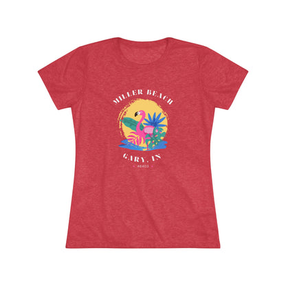 A women's triblend tee from Printify, the Miller Beach Flamingo features a blue color and "Miller Beach Gary, IN 46403" text with a vibrant design of a flamingo amidst tropical foliage for a vintage aesthetic. This t-shirt is showcased on a wooden surface alongside a denim jacket, white sneakers, and a potted plant.