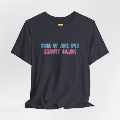 Introducing the Blues Brothers Curl Up and Dye Beauty Salon Unisex Jersey Short Sleeve Tee by Printify. This dark T-shirt features a nostalgic design with light blue and pink text that reads "CURL UP AND DYE BEAUTY SALON," reminiscent of a classic Blues Brothers tee. Crafted from 100% Airlume cotton, it is displayed against a plain light background.