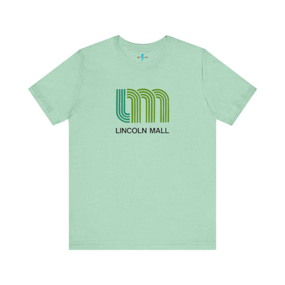 A light green unisex jersey short sleeve tee by Printify features "LINCOLN MALL" written under a retro-styled green and blue curved line design, celebrating the 70s and 80s shopping era in Lincoln Mall Matteson.