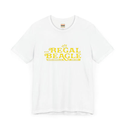 The Printify Regal Beagle - Three's Company Unisex Jersey Short Sleeve Tee, in black, showcases "The Regal Beagle, Santa Monica, CA, Est. 1977" text in a yellow vintage-style font. Crafted from 100% Airlume combed cotton for superior comfort.