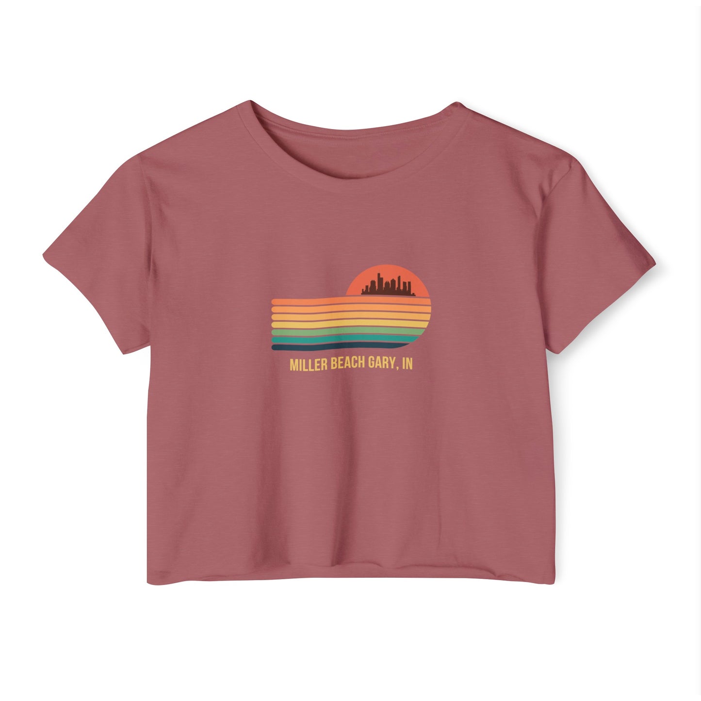 The Miller Beach Gary, IN Gradient Sunset - Women's Festival Crop Top by Printify is a mauve-colored T-shirt showcasing a retro-style graphic design of a sunset with multicolored stripes and a city skyline silhouette. Ideal for festival season, the text below reads "Miller Beach Gary, IN." Crafted to be soft and durable, this custom crop top provides both comfort and style throughout the day.