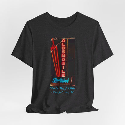 The Blue Island Illinois Steele-Hopf Oldsmobile Unisex Jersey Short Sleeve Tee by Printify features a vibrant red design with an image of a vintage neon sign. The sign displays "OLDSMOBILE" in vertical red letters and "Strafford" in blue cursive script. Below the sign, light blue text reads "Sleets Hopf Olds" and "Blue Island, IL," making it an ideal retro-inspired tee for classic car enthusiasts.