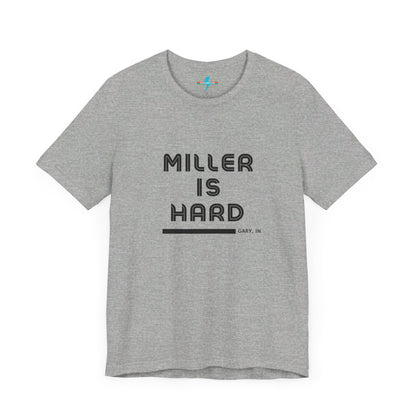 A unisex jersey short sleeve tee from Printify in burnt orange features the bold black text "MILLER IS HARD" on the chest, with "GARY, IN" written beneath in smaller black font. Perfect for showcasing Miller Beach's iconic spirit, this t-shirt is displayed against a plain white background.