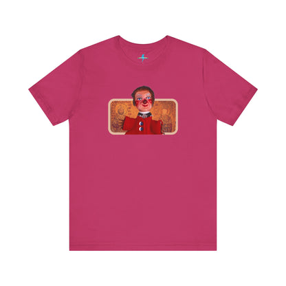 The rust-colored Printify Lady Elaine - Mr. Rogers Unisex Jersey Short Sleeve Tee features a detailed image of the Lady Elaine puppet, dressed in a red outfit with a painted face, set against an intricate artistic backdrop. The centrally positioned puppet and vivid colors create a striking contrast against the muted tone of the shirt, evoking nostalgic memories of Mr. Rogers' Neighborhood.