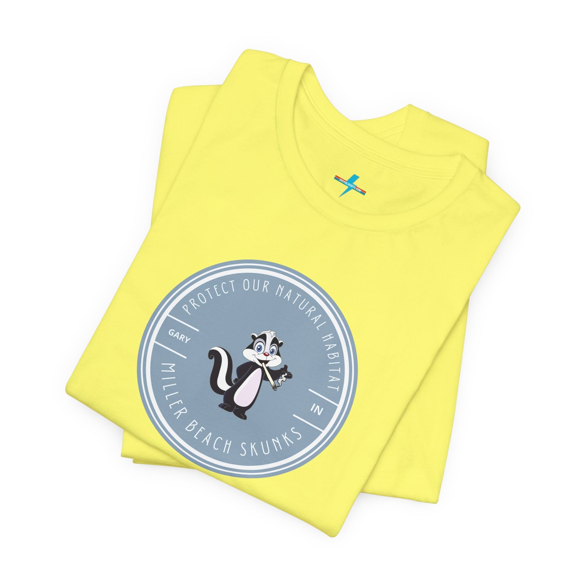 The Printify Miller Beach Skunks - Unisex Jersey Short Sleeve Tee is a gray T-shirt that features a circular blue logo at the center. Inside the logo, there is an illustration of a skunk with the text "Protect Our Habitat" and "Miller Beach Skunks" around the border, promoting environmental consciousness. The upper left part of the logo reads "Gary, IN.